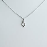 Silver necklace with a small pendant on a light gray background