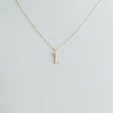 Gold necklace with a 'J' pendant on a light gray background