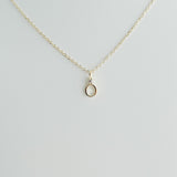 Gold necklace with a small pendant on a light gray background
