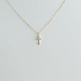 Gold necklace with a 'T' pendant on a light gray background