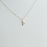 Gold necklace with a 'P' pendant on a light gray background