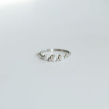 Silver ring with small stones on a light gray background