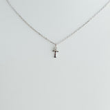 Silver necklace with a small cross pendant on a light gray background