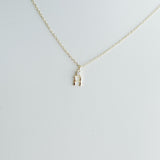 Gold necklace with a small 'H' pendant on a light gray background