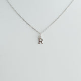 Silver necklace with a 'R' pendant on a light gray background