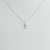 Gold necklace with a letter 'Z' pendant on a light gray background