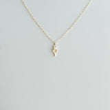 Gold necklace with a small pendant on a light gray background