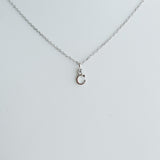 Silver necklace with a small round pendant on a light gray background