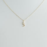 Gold necklace with a 'S' pendant on a light gray background