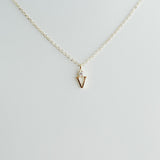 Gold necklace with a small pendant on a light gray background