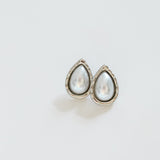 Teardrop-shaped earrings with pearl-like stones on a light gray background