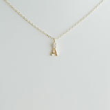 Gold necklace with a small letter 'A' pendant on a light gray background