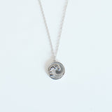 Silver necklace with a circular pendant on a white background