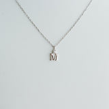 Silver necklace with a 'M' pendant on a light gray background