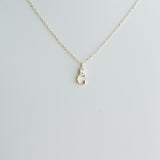 Gold necklace with a small 'C' pendant on a light gray background