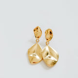 Gold earrings on a light gray background