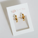 Gold earrings on a white card with 'Sweet Pea' branding on a light gray background