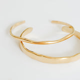 Two gold bangles on a white background