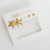 Gold starfish earrings on a white card with floral design