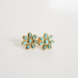 Pair of gold earrings with turquoise stones on a light gray background