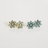 Pair of flower-shaped earrings with turquoise stones on a light gray background